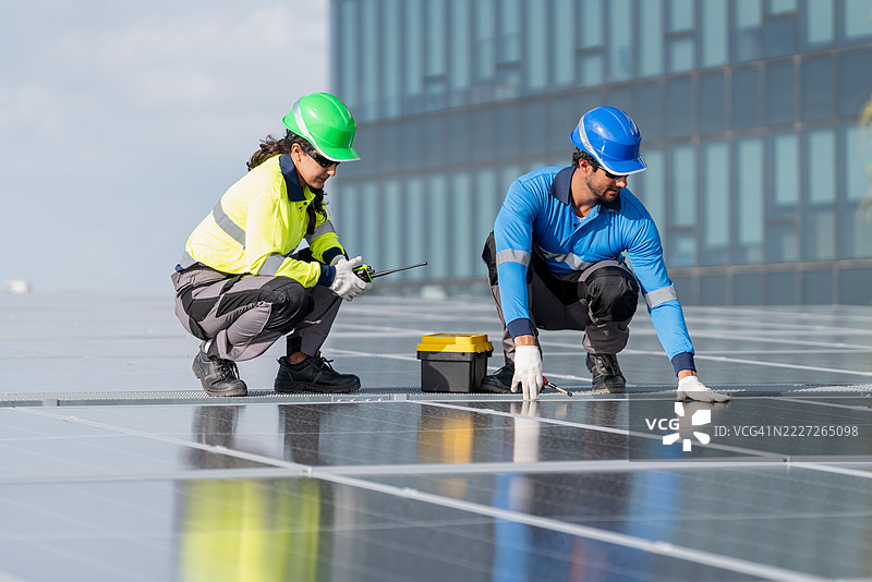 服务工程师正在检查屋顶太阳能电池板的维护情况，并检查是否有损坏的部件。技术人员还参与太阳能电池板的安装，推广清洁能源的使用。图片素材