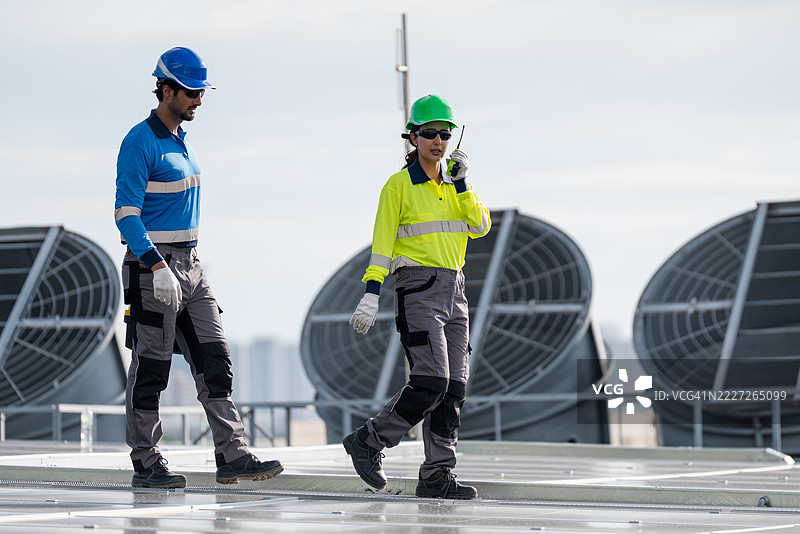 服务工程师正在检查屋顶太阳能电池板的维护情况，并检查是否有损坏的部件。技术人员还参与太阳能电池板的安装，推广清洁能源的使用。图片素材