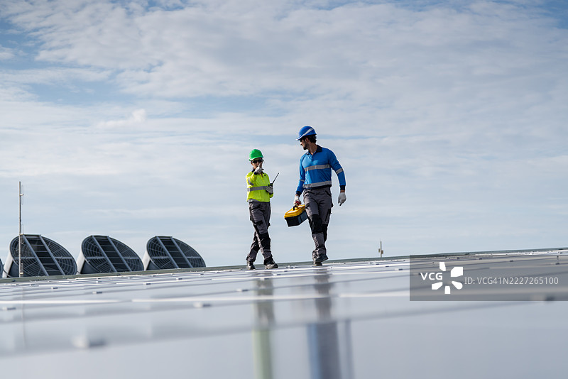 一名服务工程师正在检查屋顶太阳能电池板的维护情况，并检查是否有任何损坏的部件。该技术人员还参与太阳能电池板的安装，推广清洁能源的使用。图片素材