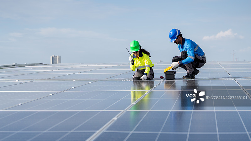 服务工程师正在检查屋顶太阳能电池板的维护情况，并检查是否有损坏的部件。技术人员还参与太阳能电池板的安装，推广清洁能源的使用。图片素材
