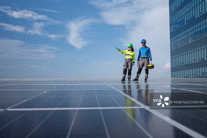 服务工程师正在检查屋顶太阳能电池板的维护情况，并检查是否有损坏的部件。技术人员还参与太阳能电池板的安装，推广清洁能源的使用。图片素材