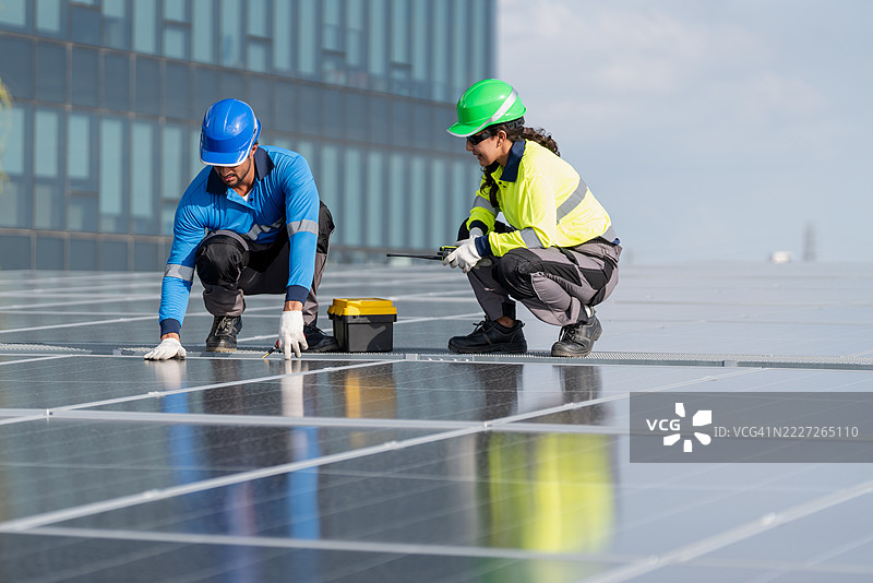 服务工程师正在检查屋顶太阳能电池板的维护情况，并检查是否有损坏的部件。技术人员还参与太阳能电池板的安装，推广清洁能源的使用。图片素材