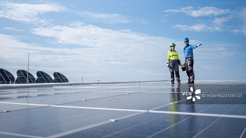 服务工程师正在检查屋顶太阳能电池板的维护情况，并检查是否有任何损坏的部件。技术人员还参与太阳能电池板的安装，推广清洁能源的使用。图片素材