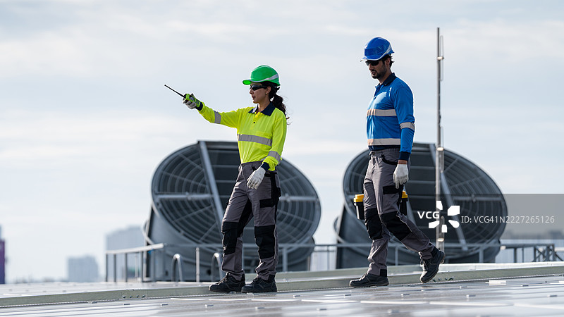 服务工程师正在检查屋顶太阳能电池板的维护情况，并检查是否有任何损坏的部件。技术人员还参与太阳能电池板的安装，推广清洁能源的使用。图片素材