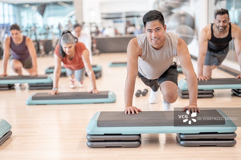 现代健身房环境中的团体健身课程进行踏板锻炼图片素材