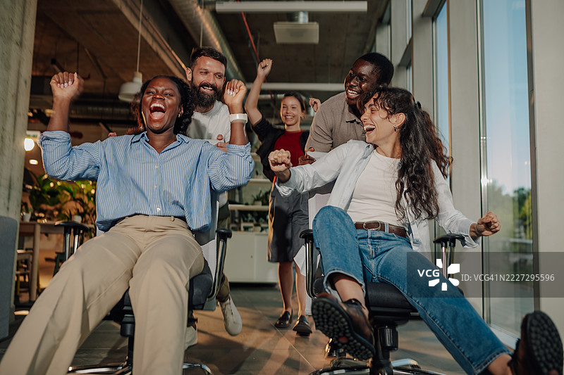 兴奋的商务团队在办公椅上比赛，玩得很开心图片素材