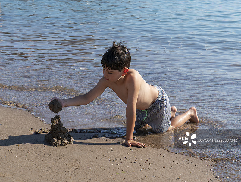 小男孩在海滩上玩沙子图片素材