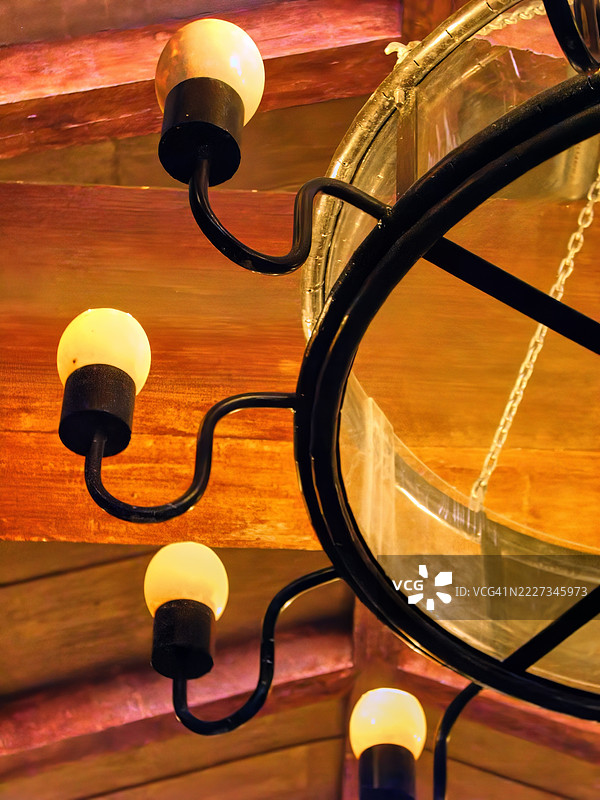 一个温暖发光的灯具特写，带有弯曲的金属臂和圆形框架。图片素材