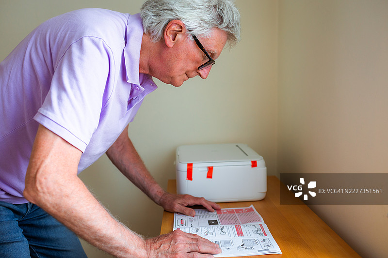 老年男子在家办公室安装新打印机图片素材