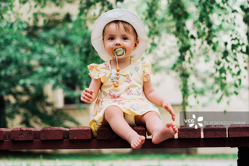 可爱的婴儿戴着帽子，在公园环境中享受户外时光图片素材
