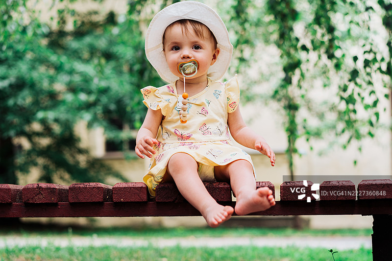 可爱的婴儿戴着帽子，在公园环境中享受户外时光图片素材