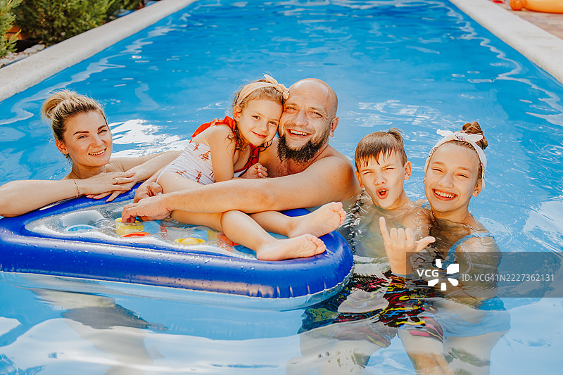 家庭在泳池中的夏日时光。图片素材