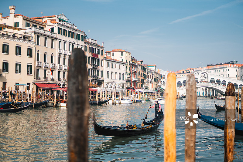 贡多拉船夫在威尼斯运河上航行，为游客提供靠近里亚尔托桥的风景游览。图片素材