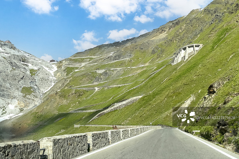 阿尔卑斯山斯特尔维奥山口的东坡上升至下降的景观，右上角是建在陡坡上的石砌蛇形路，背景中央有许多发夹弯曲的蛇形道路通向海拔2757米和2758米的山口。图片素材