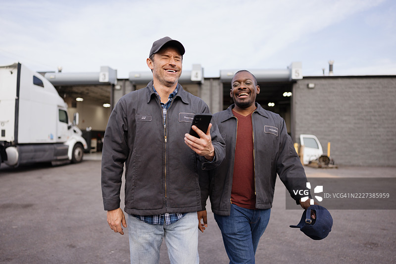 卡车司机们在欢笑并使用智能手机应用程序图片素材