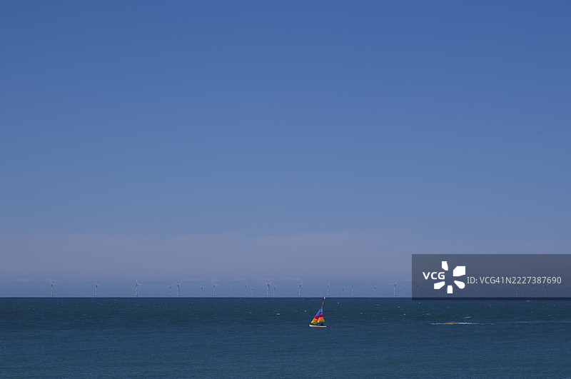 帆船，五彩斑斓的帆，在海上航行，天空湛蓝，位于离岸风电场后方，风力涡轮机，埃特雷塔，诺曼底，塞纳-马恩，法国图片素材