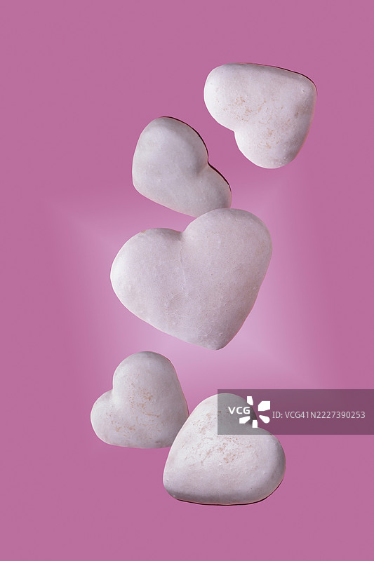 白色心形饼干在粉色背景上飞舞图片素材