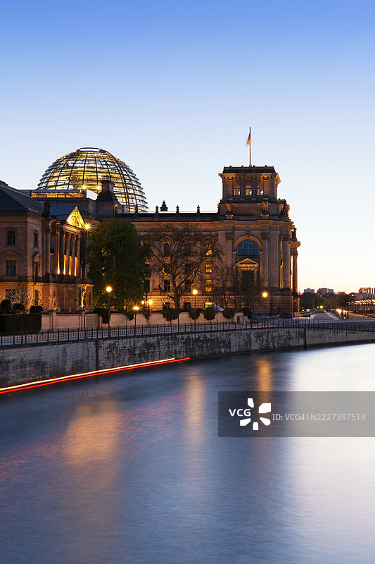 德国联邦议院位于施普雷河旁 - 国会大厦在蓝色时刻飘扬着德国国旗（德国议会大楼） - 柏林，德国图片素材