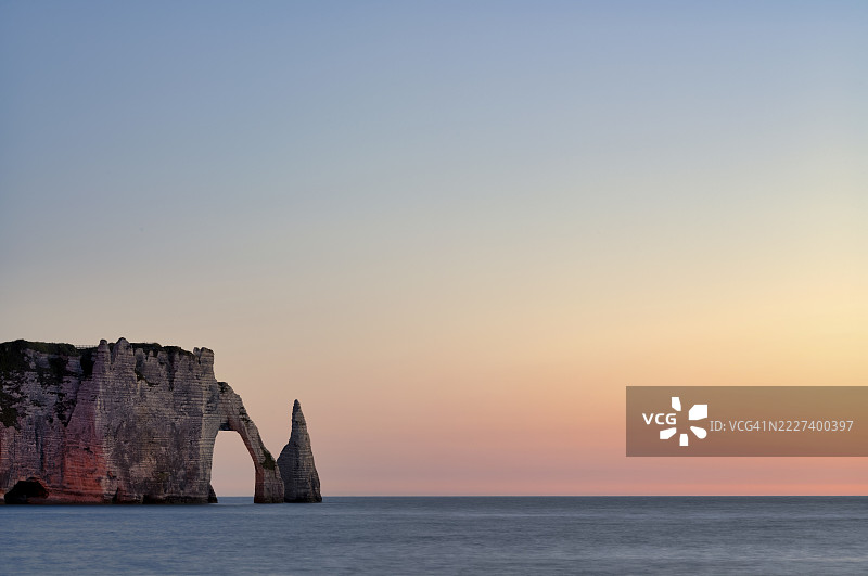 法莱兹岩拱门或阿瓦尔门与岩针艾吉尔，灯光照耀，埃特雷塔，海洋，陡峭的海岸，悬崖，白垩悬崖，白色海岸，诺曼底，塞纳-马恩省，法国，日落，傍晚氛围，富有情调。图片素材