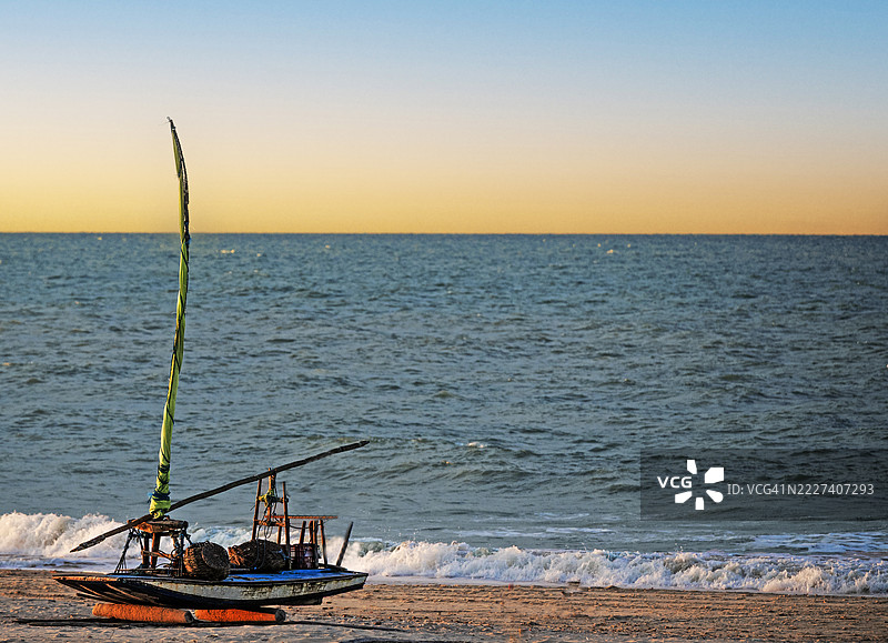 沙滩上停着一艘面朝大海的独木舟，夕阳西下。图片素材