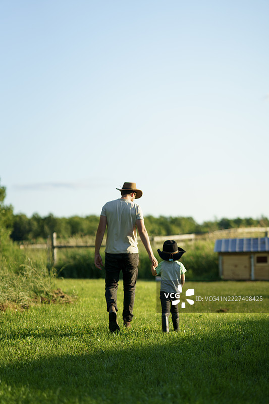 父亲和孩子在日落时分的田园乡村田野散步图片素材
