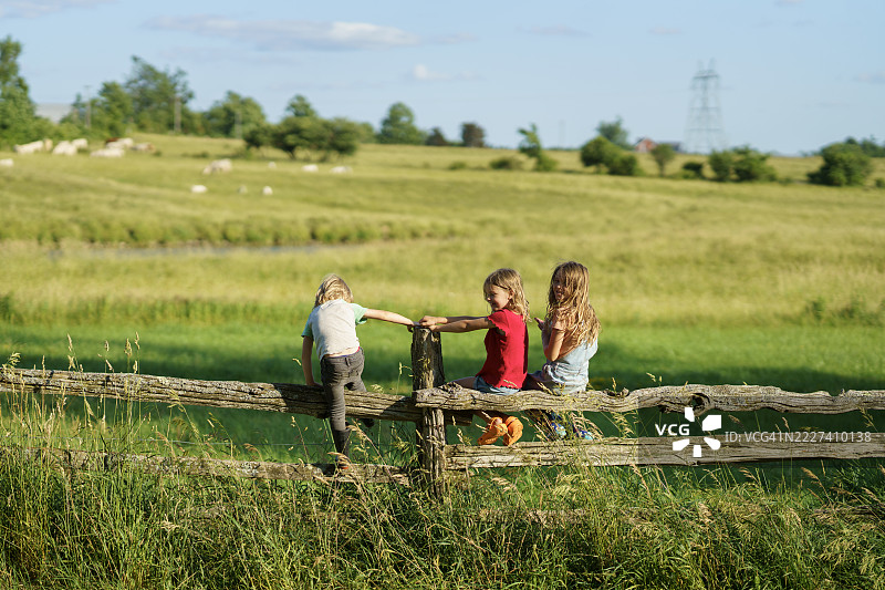 孩子们在乡村的木栅栏上享受玩耍时光图片素材