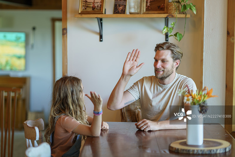 父亲和女儿在家中桌子旁享受击掌的快乐图片素材