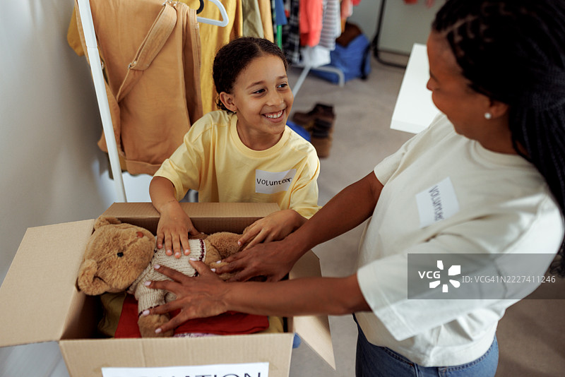 母亲和女儿正在把捐赠物品装进纸箱里图片素材