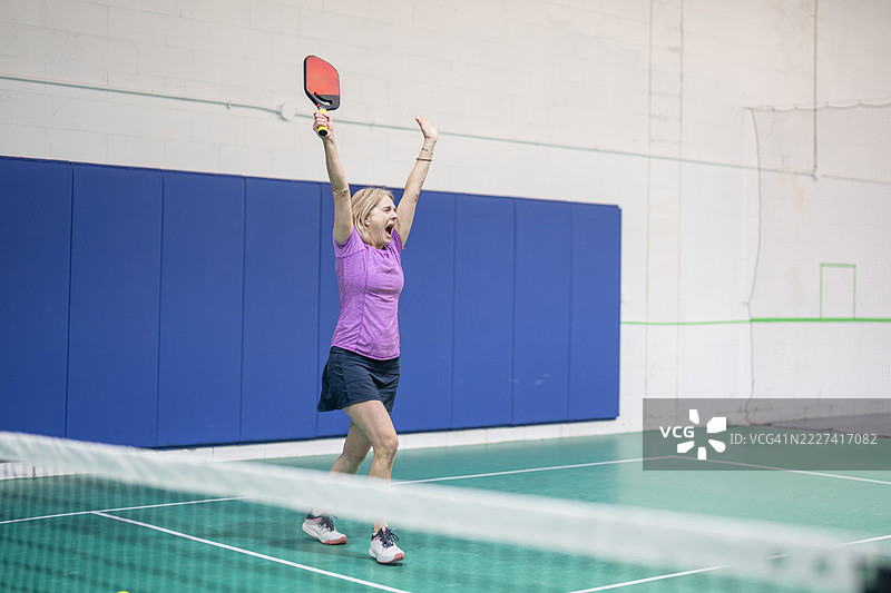 女性在绿色场地的室内皮克球比赛中庆祝胜利图片素材