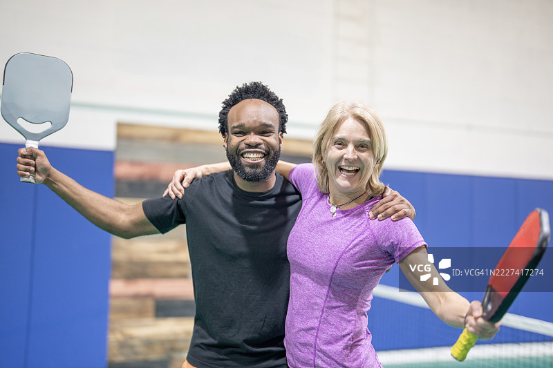 微笑的朋友们在室内球场上拿着皮克球拍图片素材