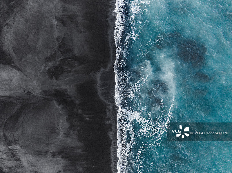 从无人机正上方拍摄的海浪涌向火山沙滩，位于印度尼西亚巴厘岛克伦贡区图片素材