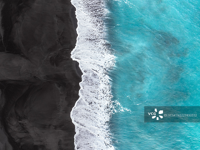 壮观的无人机图像展示了印度洋碧绿海水拍打在巴厘岛克伦贡区黑沙滩上的浪潮。图片素材