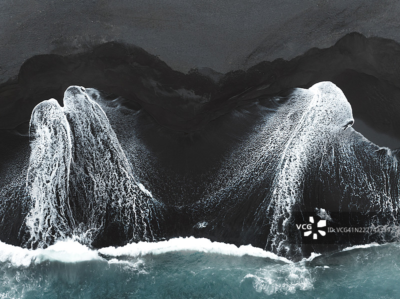 无人机拍摄的照片，俯瞰两股强大的海浪冲击巴厘岛克伦贡区的火山沙滩。图片素材