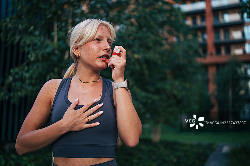 年轻的运动女性在哮喘发作时使用吸入器图片素材