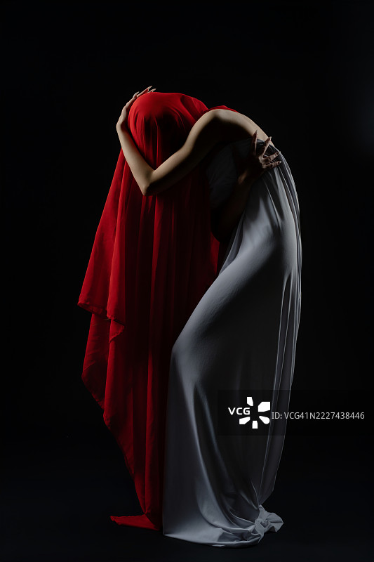 模特在戏剧化的时尚场景中，身着飘逸的织物，优雅地摆出姿势。图片素材