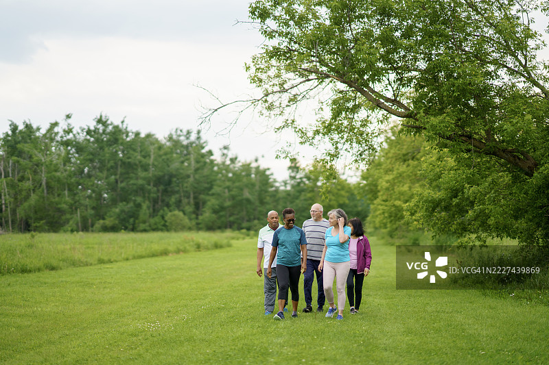 一群老年人在郁郁葱葱的公园里一起散步图片素材