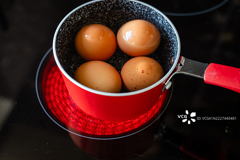 红色平底锅上煮着鸡蛋的电炉图片素材
