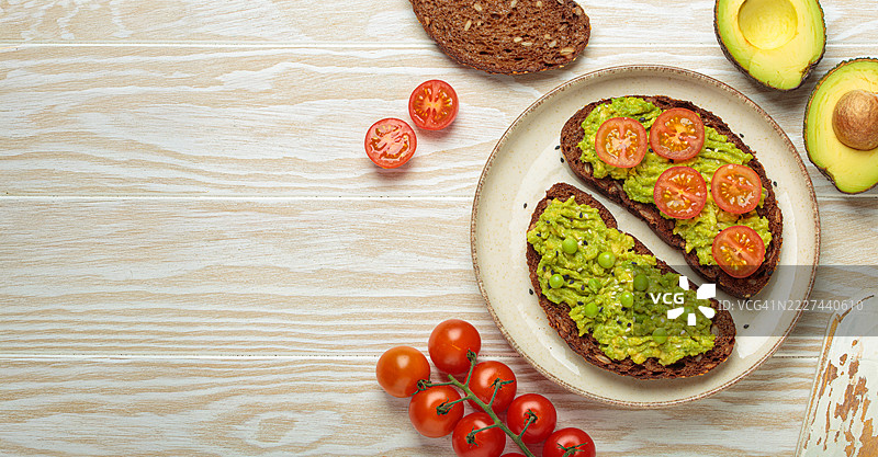 健康早餐：黑麦面包上放有牛油果、西红柿和豌豆图片素材