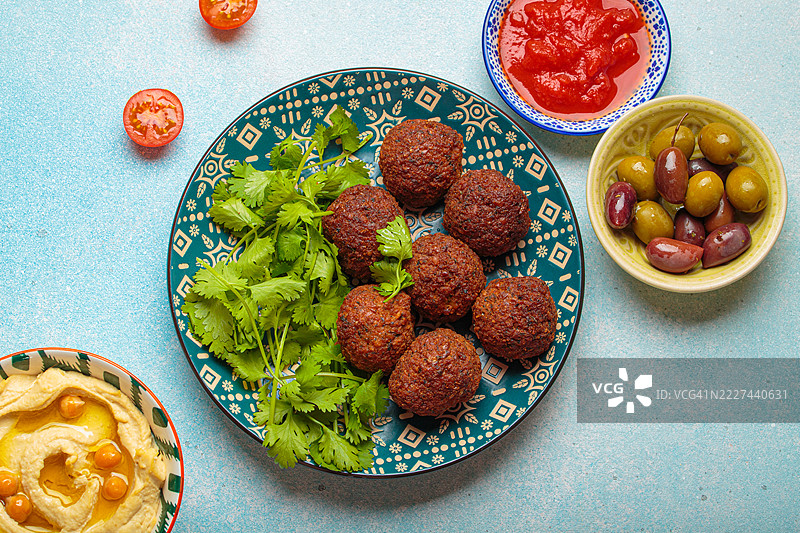 带有番茄酱、绿橄榄和香菜叶的法拉费尔，背景为蓝色图片素材