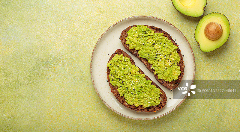盘子上放着涂有鳄梨泥和撒有芝麻的黑麦面包片图片素材