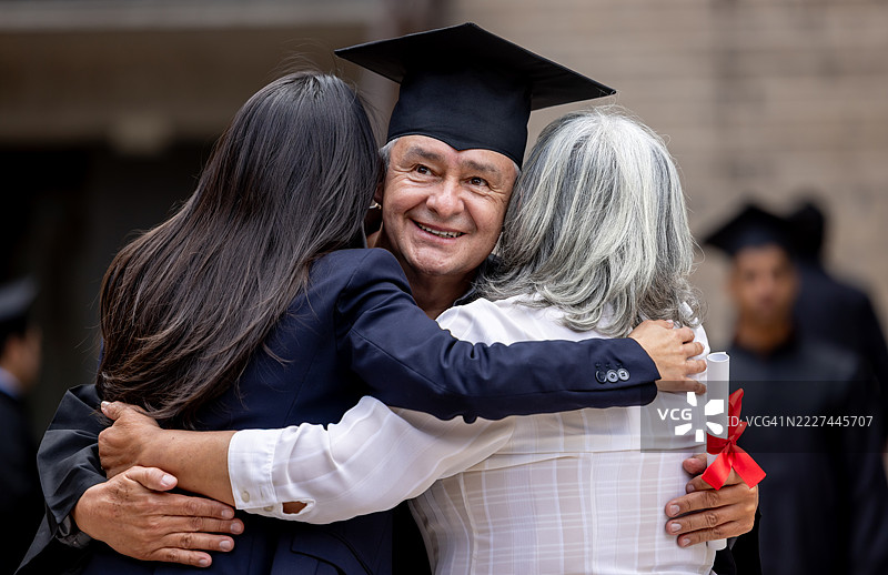 成熟的研究生在典礼后拥抱他的妻子和女儿图片素材