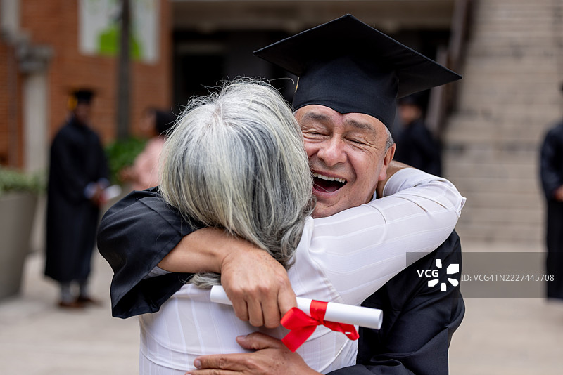 成年学生在毕业典礼后与妻子拥抱图片素材
