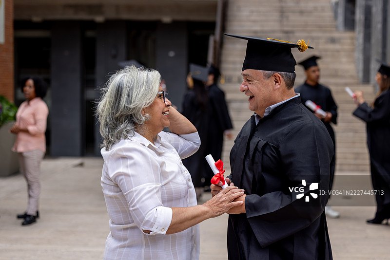 快乐的妻子在丈夫的毕业典礼上祝贺他图片素材