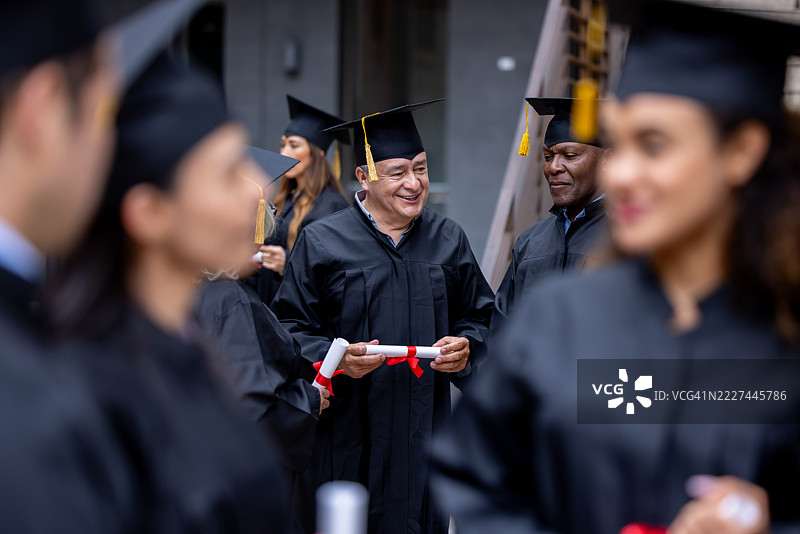 成熟男性毕业，面带笑容与同学交谈图片素材