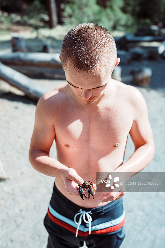 在河边的少年，手里拿着小龙虾，患有唐氏综合症。图片素材