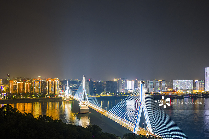 现代桥梁的鸟瞰图，夜间灯光璀璨，现代连接概念图片素材