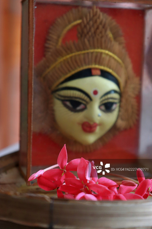 美丽的女神杜尔迦陶土达汉面像，配有红色的栀子花/西印度茉莉花，放在竹制托盘/库洛/索普上，庆祝纳瓦拉特里/杜尔迦普贾节。图片素材