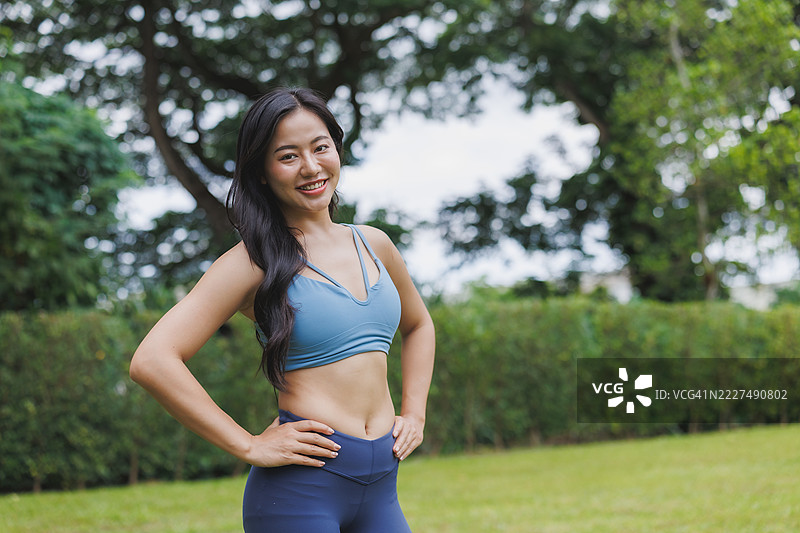 年轻的亚洲女性在公园里微笑并摆姿势，穿着运动服图片素材