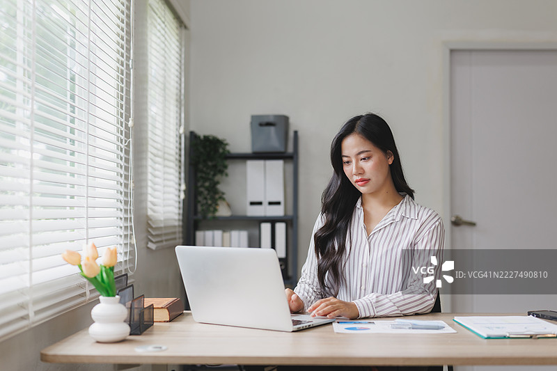 年轻的亚洲女商人在家中使用笔记本电脑工作图片素材