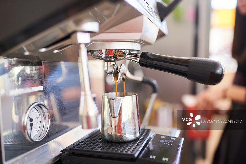 咖啡机特写，正在将浓缩咖啡冲入奶泡壶中图片素材